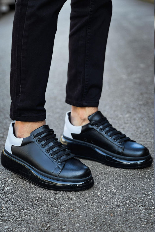 Black leather shoes worn with black pants on a pavement background